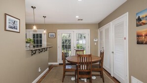 A dining area with a round table, chairs, pendant lights, and a view of the outdoors through glass doors. - Come to Pensacola White Sand beaches, in a great location 🏚️ (Pensacola)