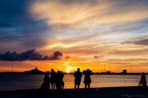 A sunset over a body of water with silhouettes of people and a yacht. - Tropical Breezes at The Truman Annex in Key West (Key West)