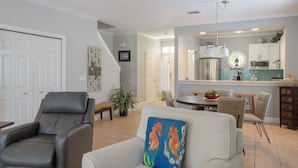 A spacious living room with a sofa, a recliner, and a dining area with a table and chairs.