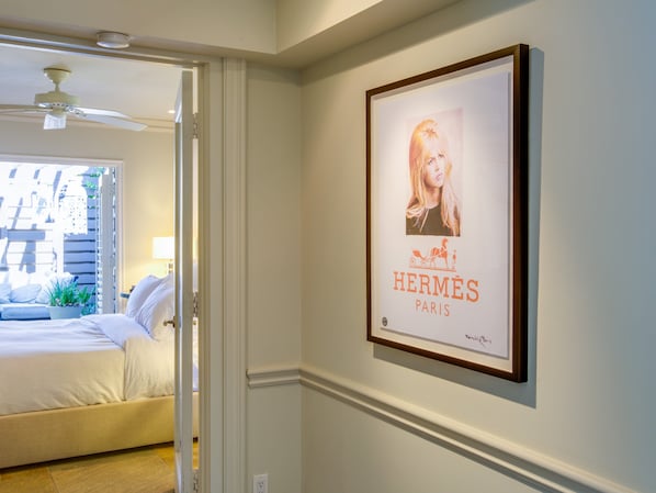 Une chambre à coucher avec un lit, un ventilateur de plafond et une porte donnant sur une autre pièce.