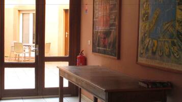 A room with a wooden table, a fire extinguisher, and a door leading to an outdoor area with chairs.