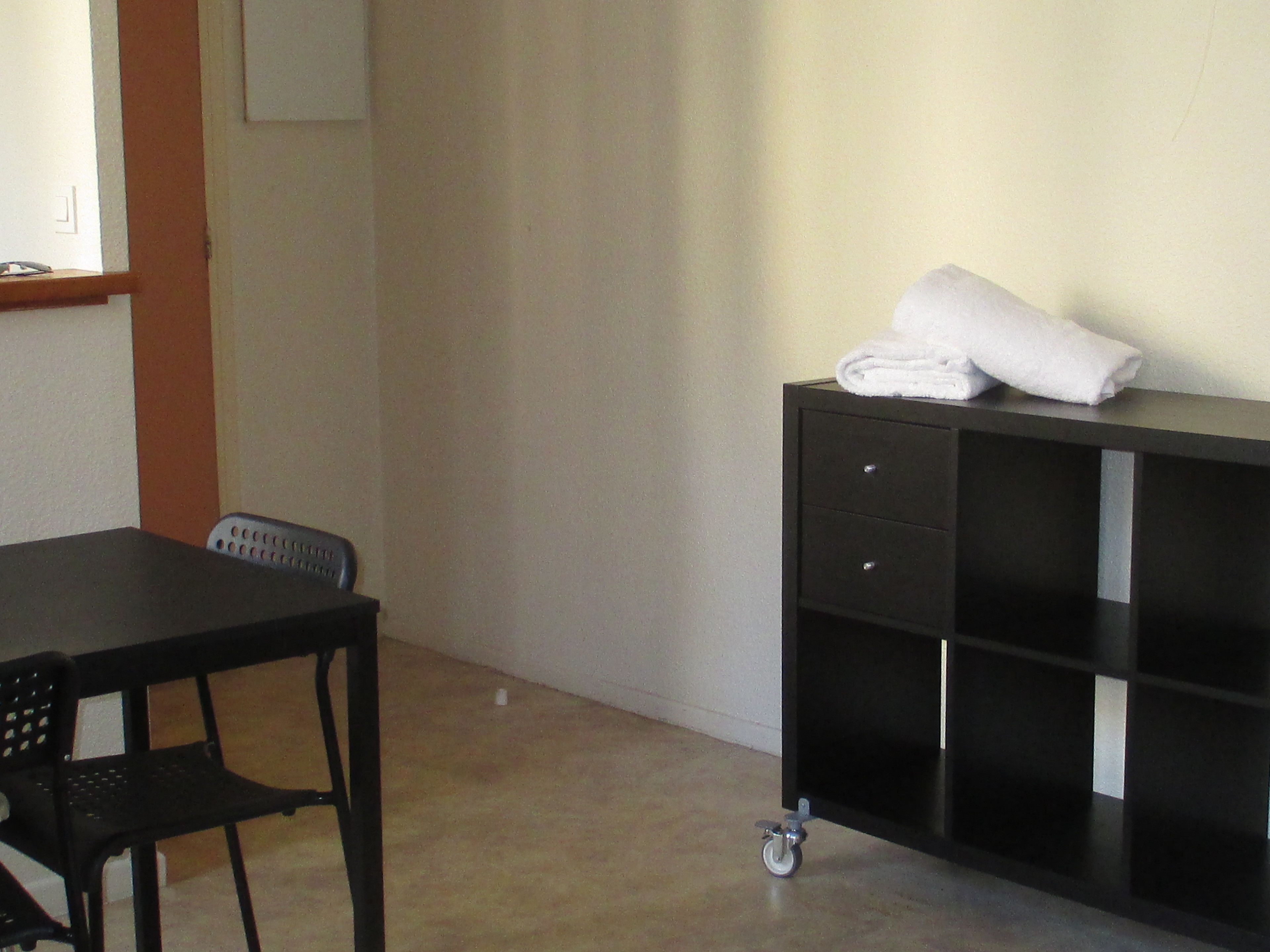 A room with a black desk, a chair, and a black storage unit with wheels.