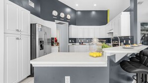 Une cuisine moderne avec des armoires blanches, un îlot central et un mur d’accent noir.