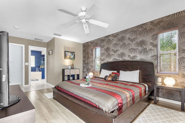 A bedroom with a large bed, a ceiling fan, a nightstand, and a window with blinds. - Pet Friendly,Gulf Access Villa w/ Pool, & kayaks! -Villa Dantasy- Roelens Vacations (CAPE CORAL)
