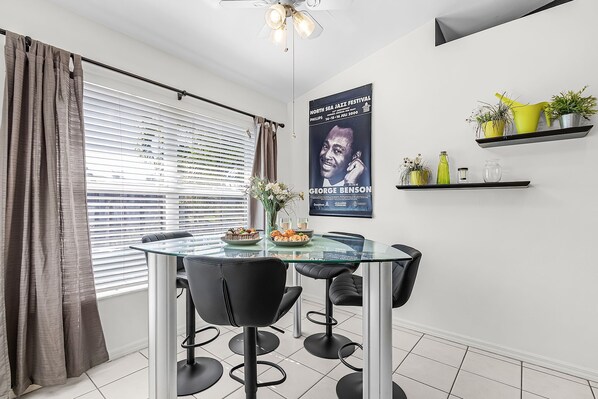 Un comedor moderno con una mesa de vidrio, sillas negras y un cartel en la pared.