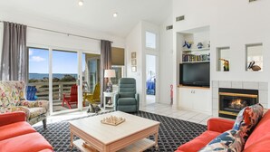 Un salón amplio con un ventanal grande, una chimenea y un balcón con vistas.