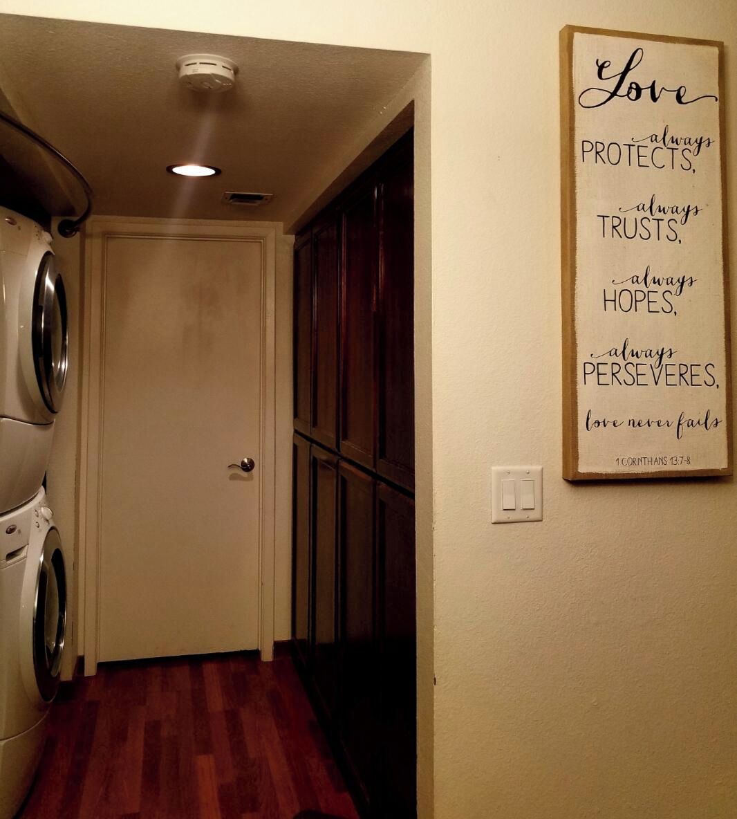 A laundry room with a washing machine, a dryer, and a wooden floor.