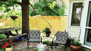 Un espace patio aménagé avec une table et des chaises en bois, une plante en pot et un vase décoratif.