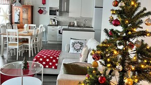 Ein modernes Wohnzimmer mit Essbereich, einer Küche im Hintergrund und einem geschmückten Weihnachtsbaum.
