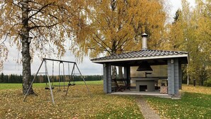 Ein Pavillon mit Kamin, einer Schaukel und einem mit Herbstlaub bedeckten Weg.