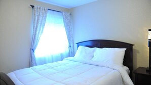 Una cama bien hecha con ropa de cama blanca en una habitación de hotel.