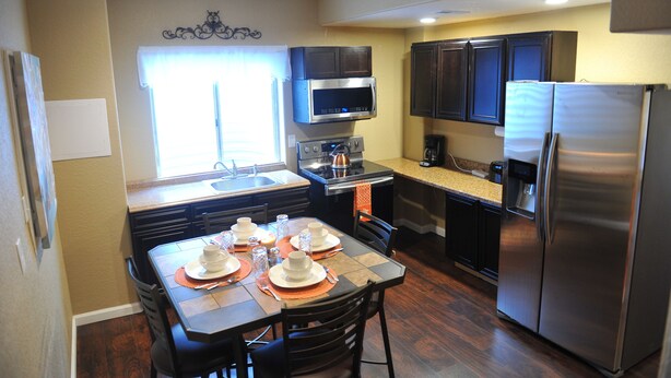 Una cocina moderna con comedor, electrodomésticos de acero inoxidable y una ventana con cortinas.