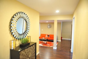 Enter a stylish living space with a circular mirror, console table, and vibrant sofa.