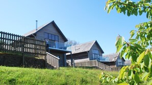 A modern house with a wooden deck and a stone wall. - Beautiful holiday home with hot tub, just a walk away from Talland beach... (Looe)