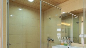 A bathroom with a glass shower enclosure, a white sink, and a mirror. - Color Fun Inn (Kaohsiung)