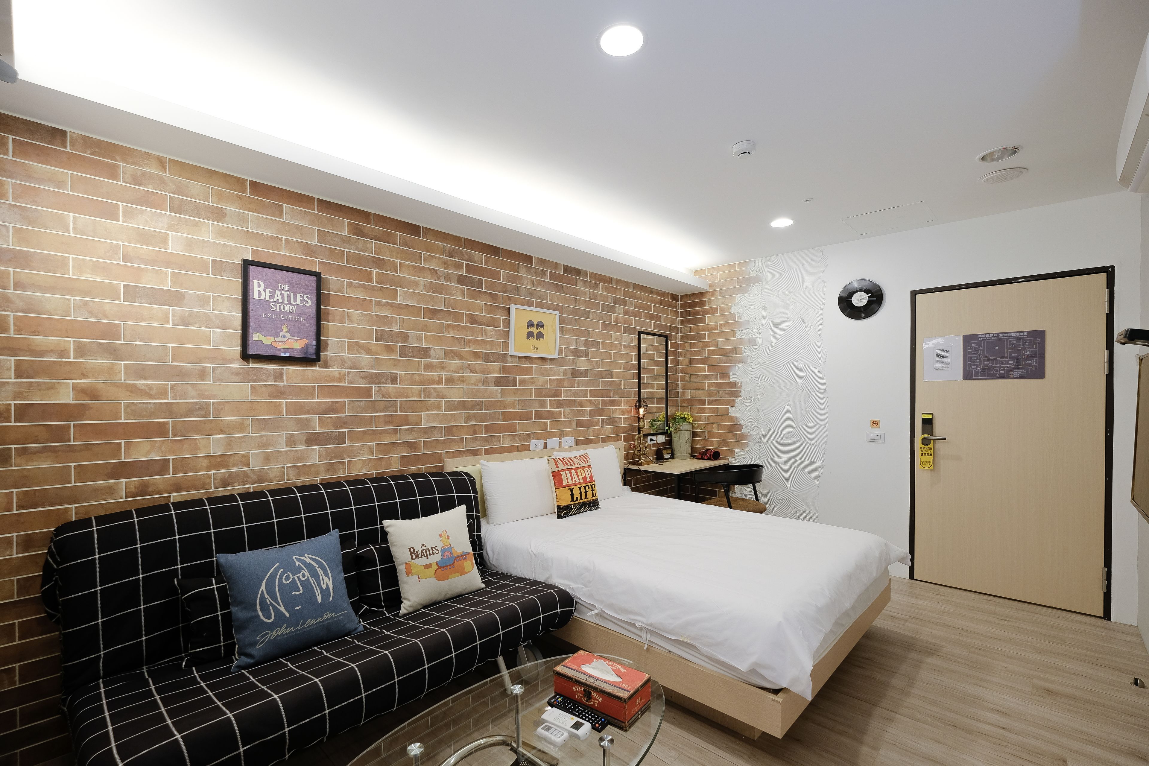 A hotel room with a brick wall, a bed, a sofa, and a small table with a box.