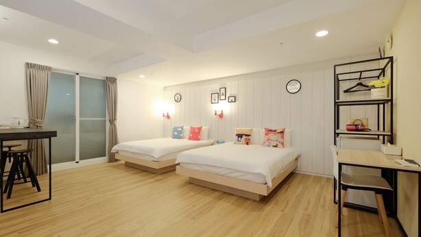 A modern hotel room with two single beds, a desk, a chair, and a small seating area. - Color Fun Inn (Kaohsiung)