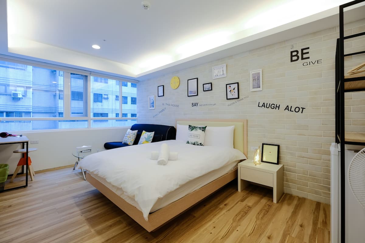 Quarto de hotel moderno com uma cama grande, uma escrivaninha e uma janela.