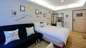A modern hotel room with a bed, a sofa, a small table, and a wall with motivational quotes and pictures. - Color Fun Inn (Kaohsiung)