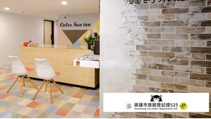 A hotel reception area with a wooden counter, white chairs, and a colorful floor. A sign reads "Color Fun inn." - Color Fun Inn (Kaohsiung)