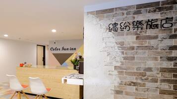 A hotel reception area with a wooden counter, white chairs, and a colorful floor. A sign reads "Color Fun inn."
