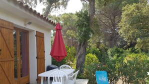 Eine Terrasse mit Tisch und Stühlen, einem roten Sonnenschirm und einem blauen Sessel.