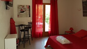 Ein Zimmer mit einem Bett, einem Schreibtisch mit Stuhl, einem kleinen Tisch mit Lampe und einem Bild an der Wand.