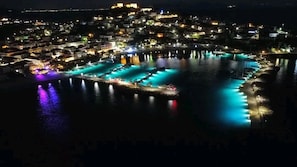 A coastal town at night with illuminated buildings and a marina.