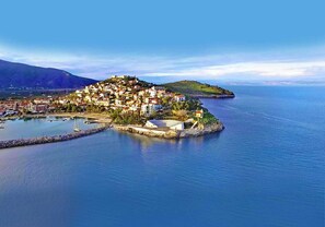 An aerial view of a coastal town with buildings clustered on a small island, connected by a causeway to the mainland.