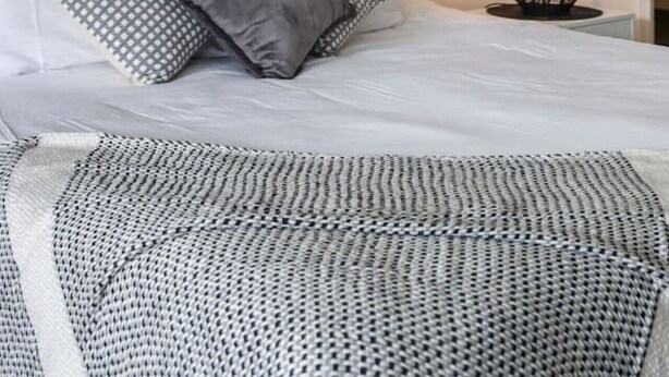 Ein Schlafzimmer mit einem Bett, Kissen, einer Nachttischlampe und einem Wandbild.