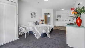 Ein kleines Zimmer mit einem Bett, einer Sitzecke, einer Küchenzeile und einem Badezimmer.