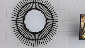 Ein runder Tisch mit Stühlen, eine an der Wand befestigte, runde Metallverzierung in Schwarz und ein gerahmtes Bild auf einem Regal.