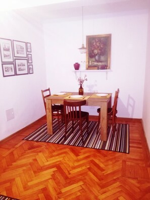 Un coin repas avec une table en bois, des chaises, un vase de fleurs et des tableaux encadrés accrochés au mur.