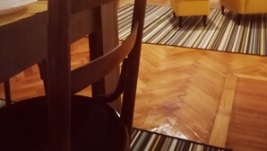 Un coin repas avec une table et des chaises en bois, un téléviseur et un fauteuil jaune.