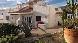 A white building with a red-tiled roof, a satellite dish, and a small balcony. - Casa Jomy, a beautiful place! Sea views! (Campello)