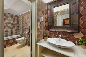 Une salle de bain dotée d’une douche à parois de verre, d’un lavabo blanc et d’un miroir avec un cadre décoratif.