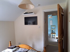 A bedroom with a bed, a television, and a door leading to another room.