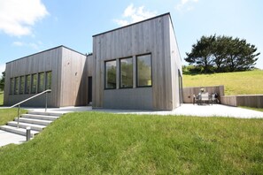 Een modern gebouw met een betonnen gevel, grote ramen en een trap naar de ingang.
