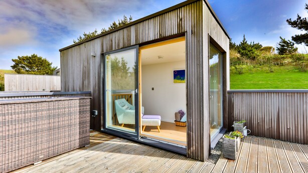 A modern, open-plan living space with a sliding glass door leading to a balcony. - Beautiful holiday home, just a walk away from Talland beach... (Looe)