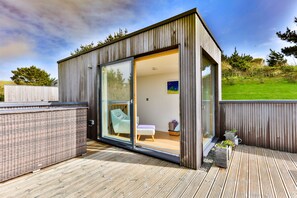 A modern, open-plan living space with a sliding glass door leading to a balcony. - Beautiful holiday home, just a walk away from Talland beach... (Looe)