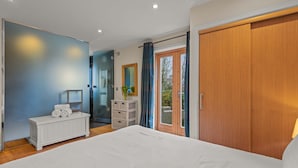 Une chambre à coucher avec un grand lit, une commode blanche, un miroir et une armoire en bois.