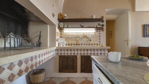 A kitchen with a tiled backsplash, wooden cabinets, and a marble countertop.