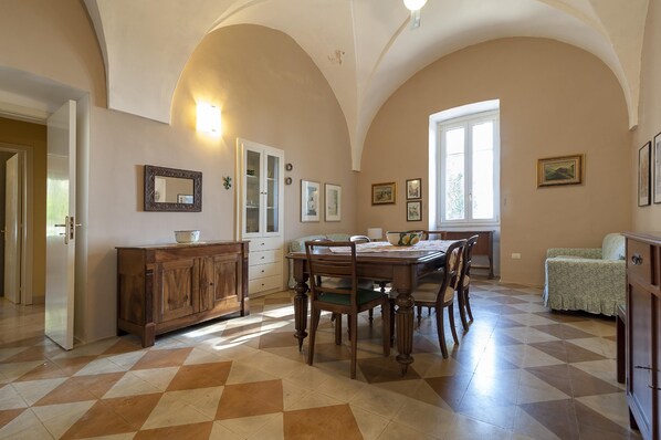 A dining area with a checkered floor, wooden furniture, and a window with natural light.