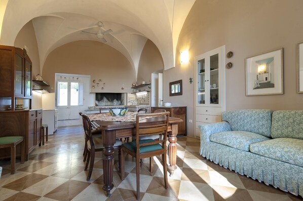 A spacious kitchen with a dining table, chairs, and a sofa.