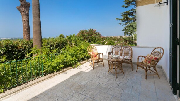 A patio with wicker furniture and a view of the sea.