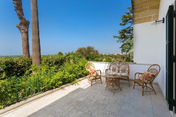 A patio with wicker furniture and a view of the sea.