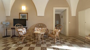 A room with a checkered floor, wicker furniture, a flat-screen TV, and a fan.