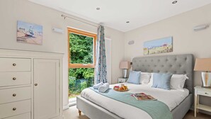 A bedroom with a bed, bedside tables, a wardrobe, and artwork on the walls. - This fantastic pet friendly,  contemporary property features a south-west facing balcony off the mas (Looe)