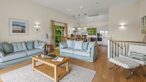 A spacious living room with two sofas, a coffee table, and a dining area. - Beautiful holiday home with hot tub, just a walk away from Talland beach... (Looe)