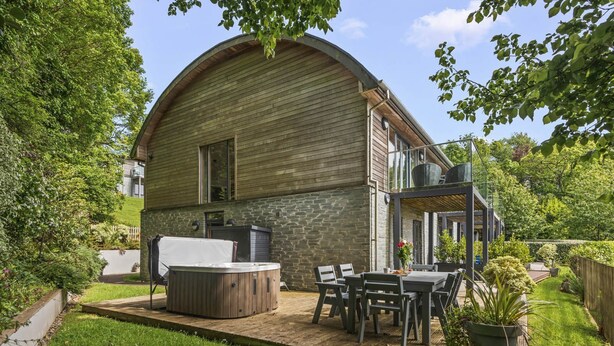 A wooden barn-style building with a hot tub, outdoor seating, and a covered patio area. - Beautiful holiday home with hot tub, just a walk away from Talland beach... (Looe)